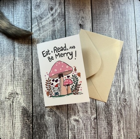 Greeting card with "Eat, Read, and Be Merry" title. Image is a cute mouse with a Santa hat under a mushroom. Shown with Kraft envelope.